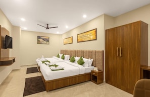A hotel room with a bed, a wardrobe, a television, and wall-mounted artwork. - One Earth Elegant (Yamkeshwar)