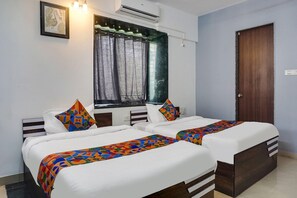 A hotel room with two beds, a window with curtains, an air conditioning unit, and a wooden door. - Fabhotel Corporate Executive (Pune)