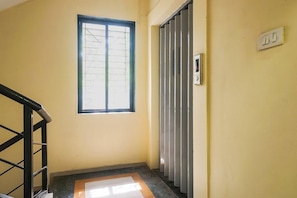Ein Flur mit einem Fenster, einer Tür mit Metallgitter und einem Lichtschalter an der Wand.