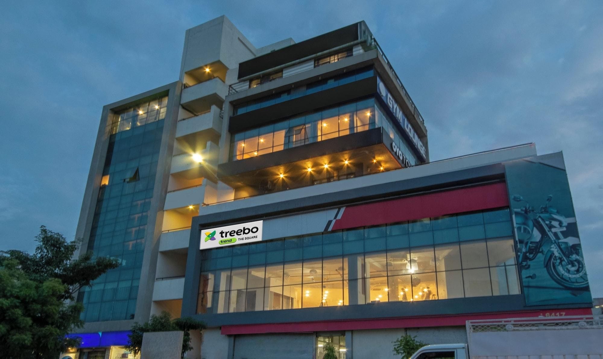 A multi-story building with a prominent 'treebo' sign, large windows, and a visible balcony area.