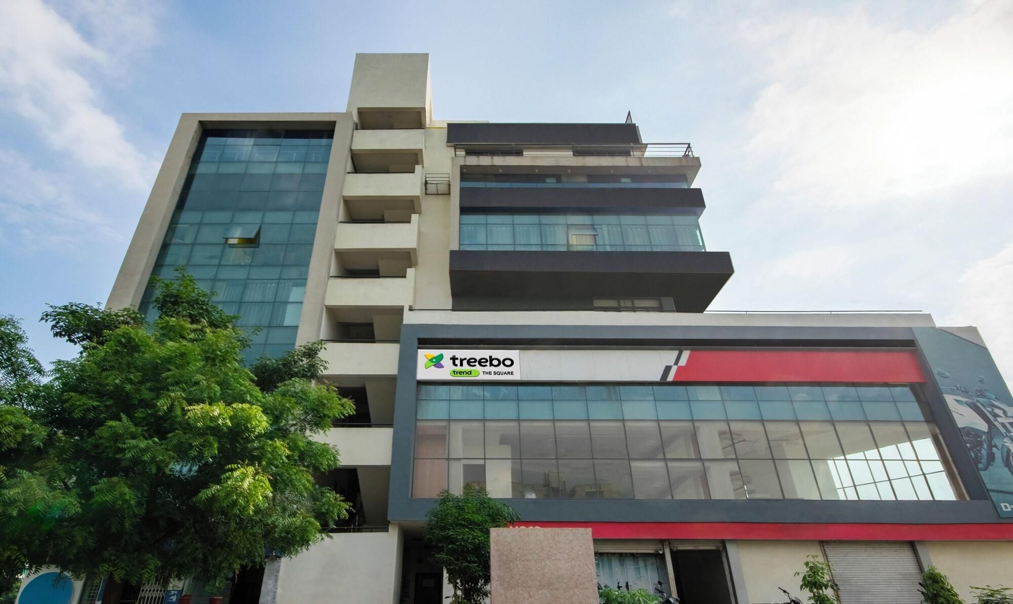 A multi-story building with a prominent 'treebo' sign on the ground floor, large glass windows, and a modern architectural design.