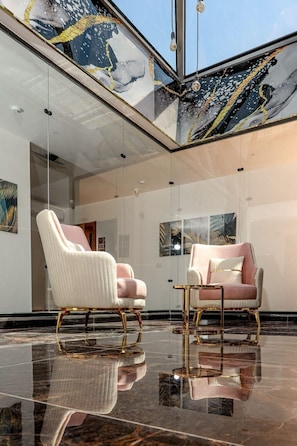 A modern interior with two plush chairs, a glass ceiling, and artwork on the walls.