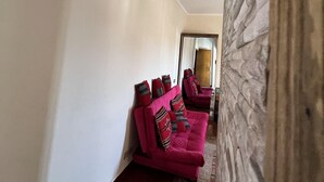 A hallway with a pink sofa set, a patterned rug, and a stone wall. - Guest House Pyramids View (Giza)