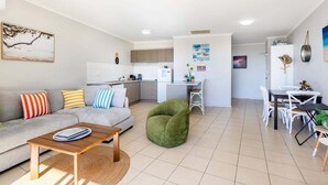 A modern apartment with a living area, kitchen, dining space, and a small office.