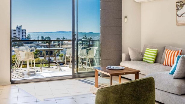 A balcony with a city view, a sofa with cushions, and a table with a book.