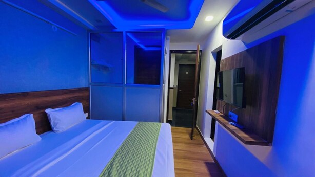 Una habitación de hotel con cama, ventilador de techo, aire acondicionado y televisor.
