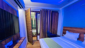 Una habitación de hotel con cama, televisor, escritorio y silla.