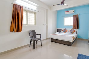 Una habitación con cama, una silla, ventilador de techo y aire acondicionado.