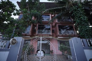 A multi-story building with a gated entrance, balconies, and lush greenery. - Hotel 7 Sea S Vagator (Vagator)