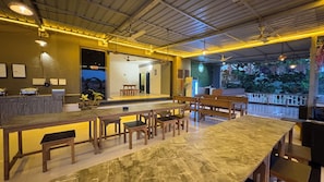 A restaurant with a marble counter, wooden chairs, and a view of the outdoors. - Hotel 7 Sea S Vagator (Vagator)