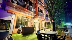 An outdoor seating area with a table and chairs, a balcony with railings, and a building facade with windows and balconies. - Hotel 7 Sea S Vagator (Vagator)