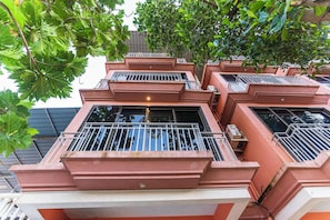 Un edificio de varios pisos con balcones, cada uno con barandillas de metal y un ventanal pequeño.