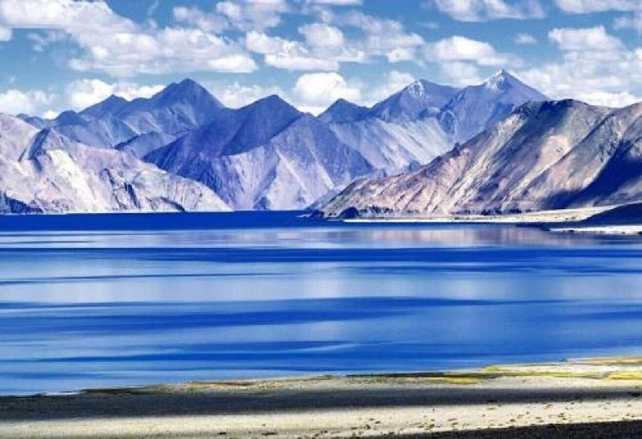 A mountain landscape with a calm lake and snow-capped peaks.