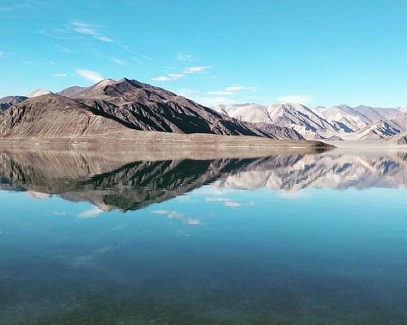 A calm lake with mountain reflections, clear skies, and no visible structures.