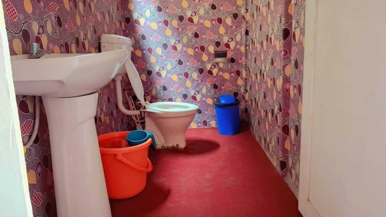 A bathroom with a patterned wall, a white sink, a toilet, and a red floor.
