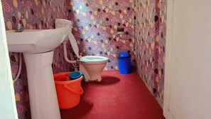 Un baño con pared estampada, un lavabo blanco, un inodoro y suelo rojo.