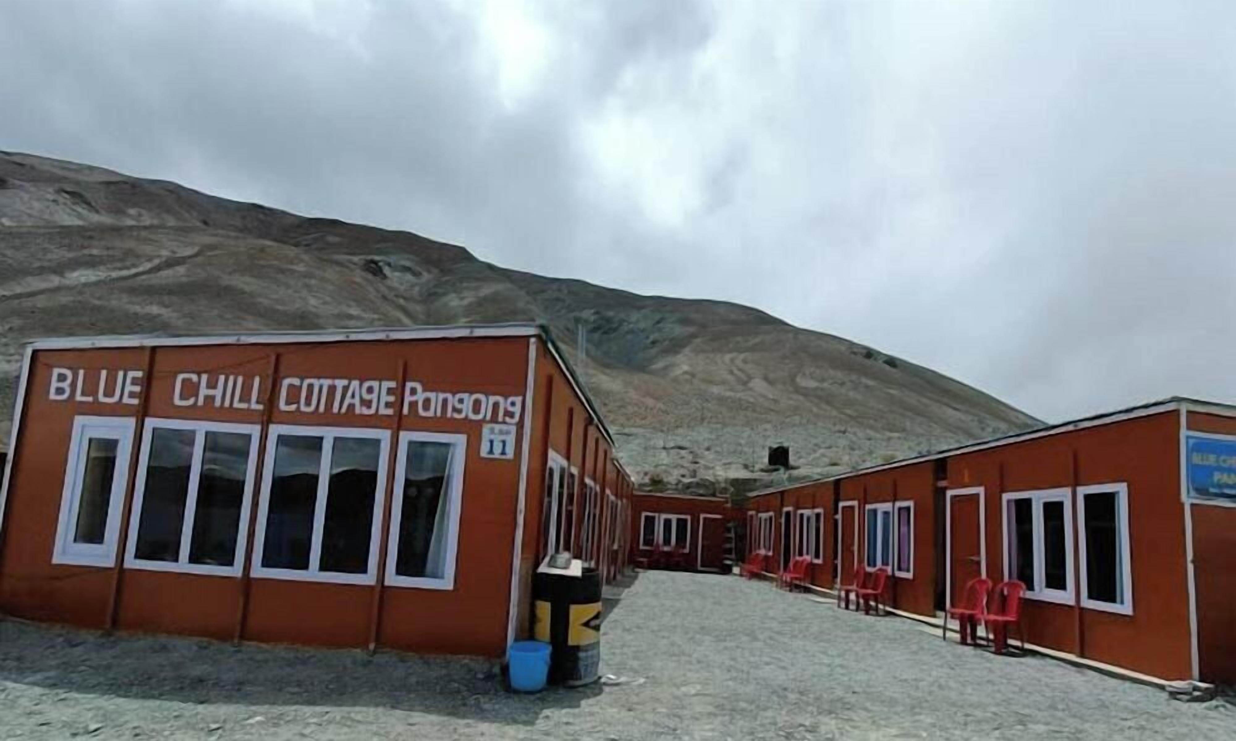 A building labeled 'Blue Chill Cottage Rangoon' with multiple windows and a gravel ground.