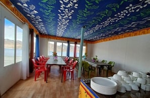 Un comedor con una mesa y sillas, vistas al exterior y un techo con diseño de hojas.