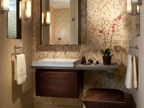 A bathroom with a white sink, a mirror, a towel rack, a potted orchid, and a leopard print bench. - Hotel Vin Inn New Delhi Railway Station (New Delhi)