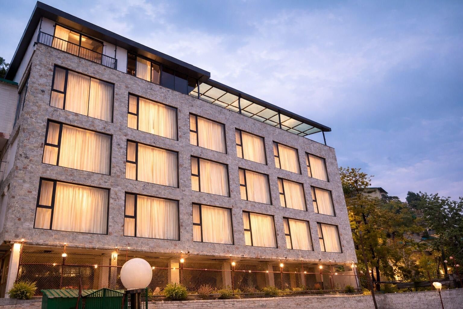 Un hôtel à plusieurs étages, doté d’une façade en pierre, de grandes fenêtres et d’un balcon situé à l’étage supérieur.