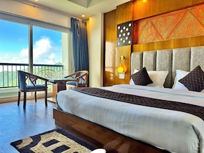 A bedroom with a large bed, a nightstand, a wall-mounted lamp, a window with curtains, and a view of the outdoors. - Ab S Abode A Boutique Hotel (Dehradun)