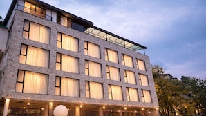 A multi-story hotel with a stone facade, large windows, and a balcony on the upper floor. - Ab S Abode A Boutique Hotel (Dehradun)