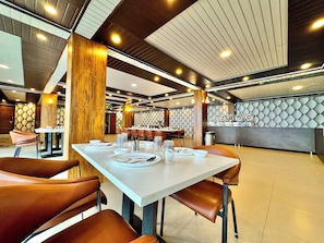 A modern dining area with wooden accents, a high ceiling, and a patterned wall. - Ab S Abode A Boutique Hotel (Dehradun)