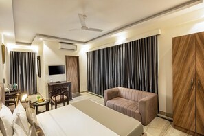 A hotel room with a bed, a seating area, a television, a desk, and a wardrobe. - The Orion Express East Of Kailash (New Delhi)