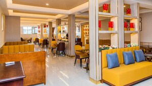 Eine Hotelhalle mit Sitzbereichen, einem Empfangstresen und einer Kaffeebar.