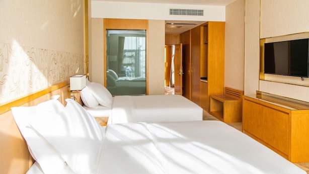 Ein Hotelzimmer mit zwei Betten, einem Fernseher, einem Schreibtisch und Blick ins Freie.
