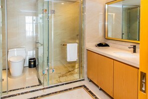 Een moderne badkamer met een douche met glazen wand, een wit toilet, een wastafel met spiegel en houten kastjes.