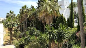 A lush garden with palm trees, cypress trees, and various shrubs. - Estepona Golf, Los Pintores (Estepona)
