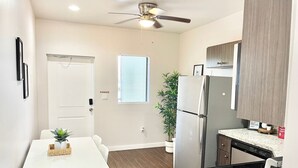 A modern kitchen with a white table, chairs, a refrigerator, a dishwasher, and a ceiling fan. - Compact 1BR Retreat | close to Miami Beach (Miami)