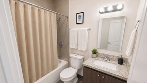 A bathroom with a bathtub, toilet, sink, and a shower curtain. - Compact 1BR Retreat | close to Miami Beach (Miami)