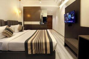 Een moderne hotelkamer met een groot bed, een aan de muur bevestigde televisie en uitzicht op de stad 's nachts.