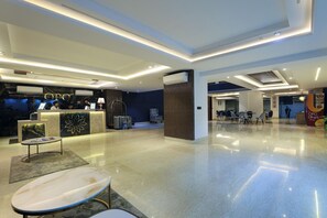 Een hotellobby met een receptiebalie, een zithoek en een eetgedeelte.