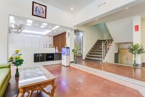 A hotel lobby with a reception desk, a staircase, and a green sofa. - Zinith Hotel (New Delhi)