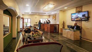 A hotel lobby with a reception desk, seating area, and a television screen. - Metropark Hotel (Mawal)