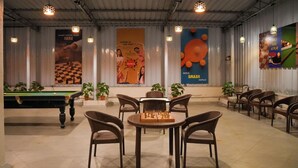 A billiards room with a pool table, chairs, and potted plants. - Metropark Hotel (Mawal)
