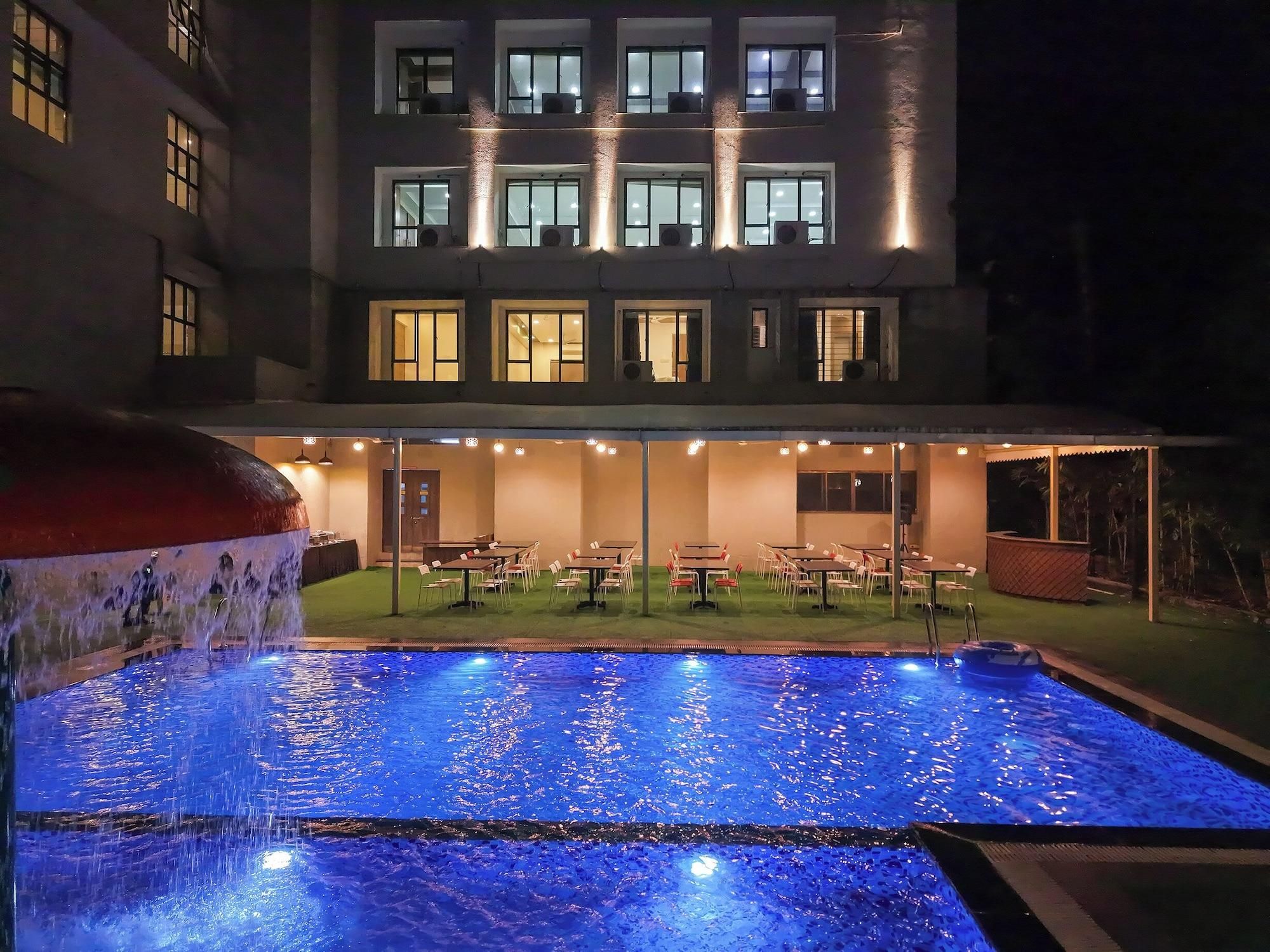 Un hotel con zona de piscina, mobiliario exterior y un edificio con múltiples ventanas.