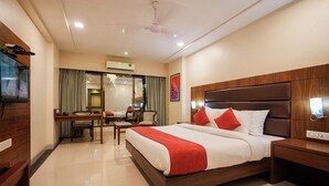 A hotel room with a bed, bedside table, and a desk with a chair. - Metropark Hotel (Mawal)