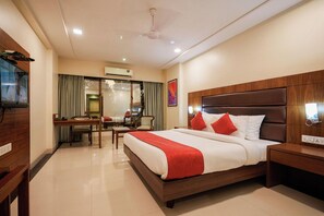 A hotel room with a bed, bedside table, and a desk with a chair. - Metropark Hotel (Mawal)