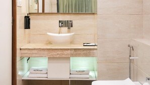 A modern bathroom with a glass-enclosed sink, a toilet, and a shower. - Metropark Hotel (Mawal)