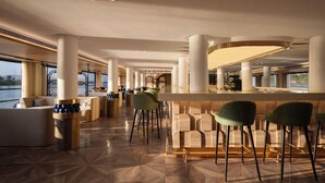 A modern bar area with high stools, a counter, and a view of the outdoors. - Soleil Nile Cruise (Cairo)