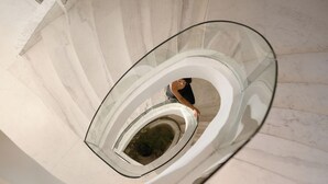 A spiral staircase with glass railings and a person descending. - Soleil Nile Cruise (Cairo)