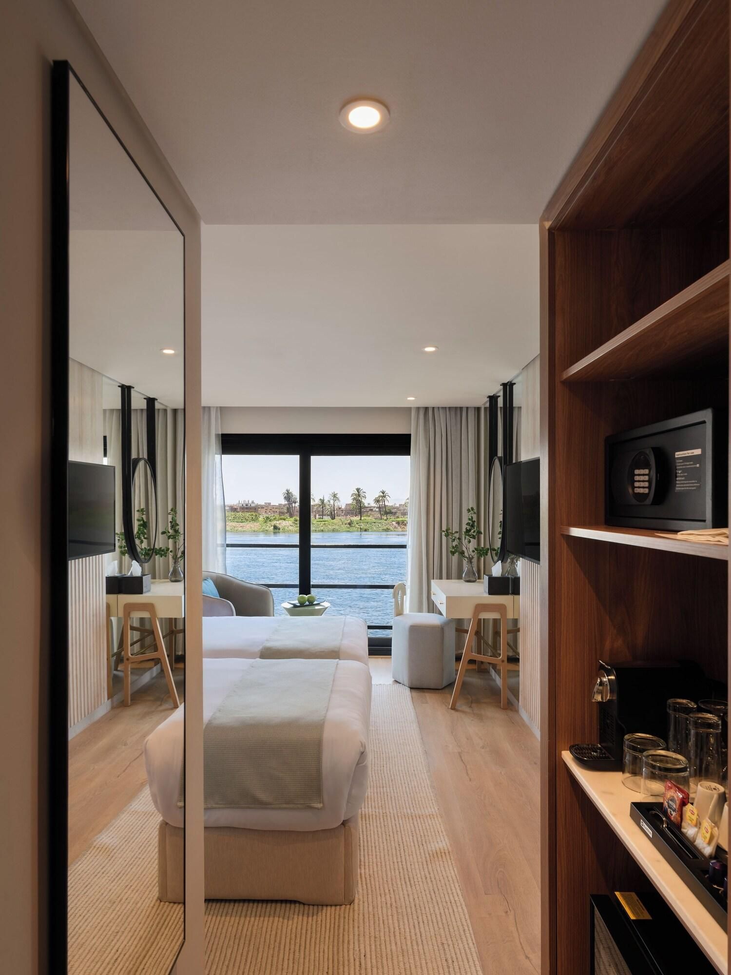 A modern hotel room with a bed, desk, and a view of the water.