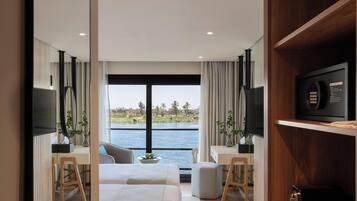 A modern hotel room with a bed, desk, and a view of the water.