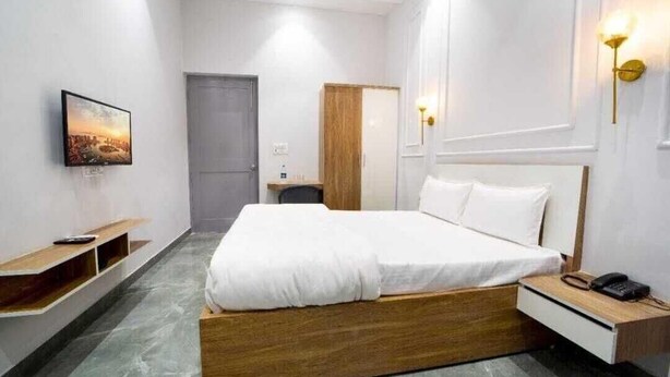 Habitació d'hotel amb un llit, una taula de nit, una làmpada i un quadre a la paret.