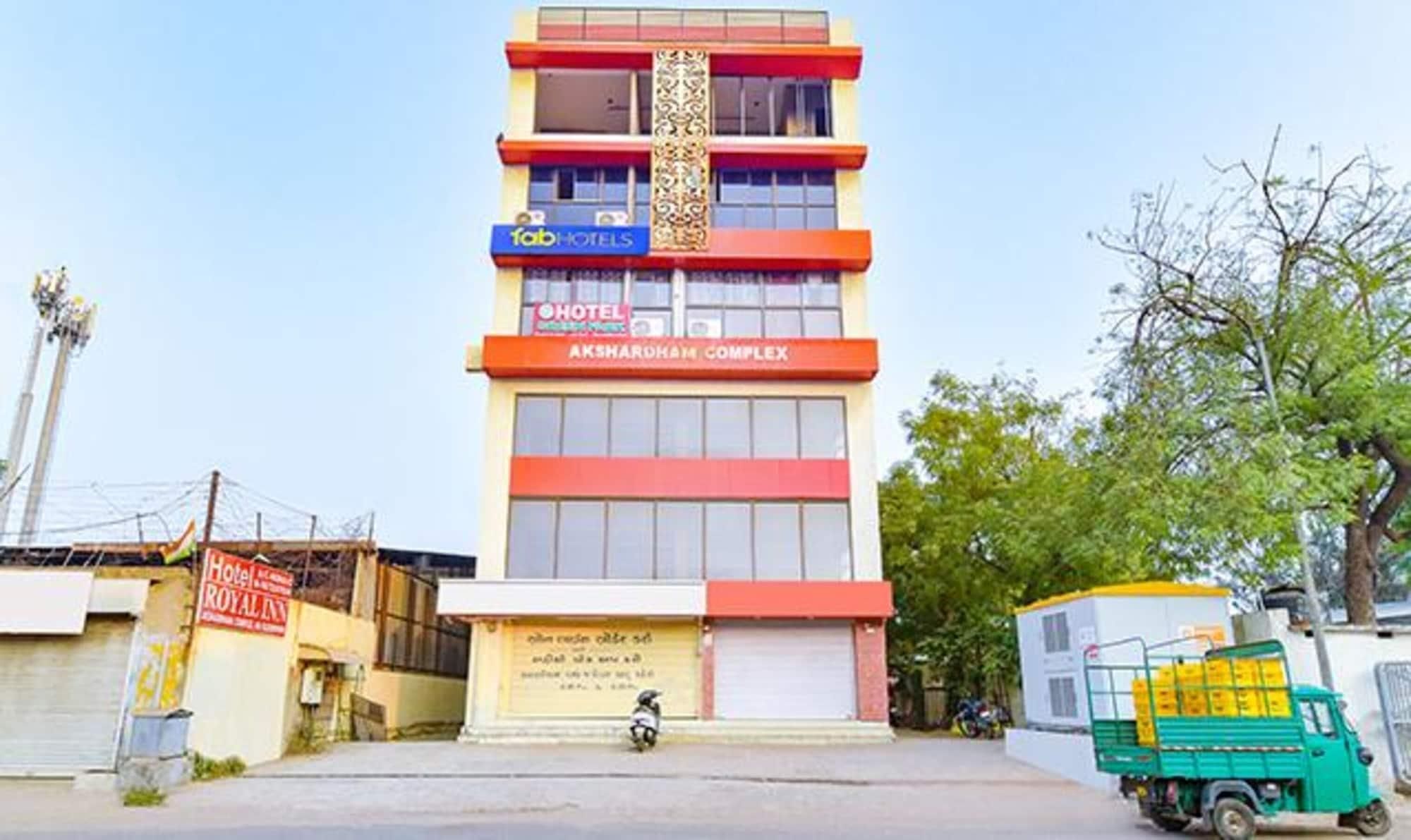 Un immeuble à plusieurs étages, avec une enseigne indiquant « Fab Hotels » et « Hotel Royal Inn » au rez-de-chaussée.