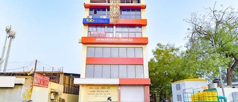Un edificio de varios pisos con un letrero que indica 'Fab Hotels' y 'Hotel Royal Inn' en la planta baja.